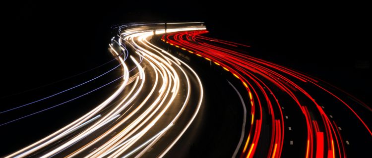 Time-lapse photo of car lights on a highway to signify the transport of data between two locations.